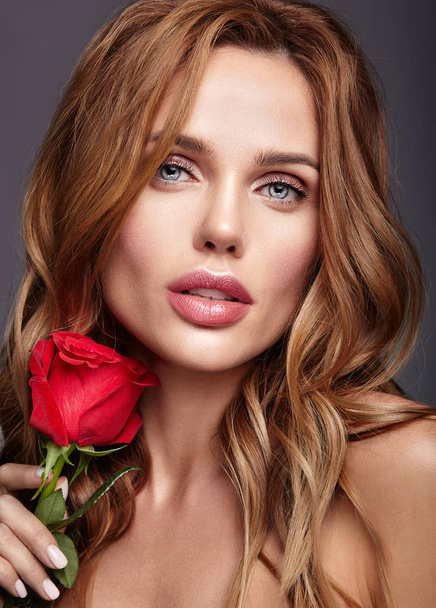 Beauty fashion portrait of young blond woman model with natural makeup and perfect skin with beautiful rose  posing in studio - Фото, зображення
