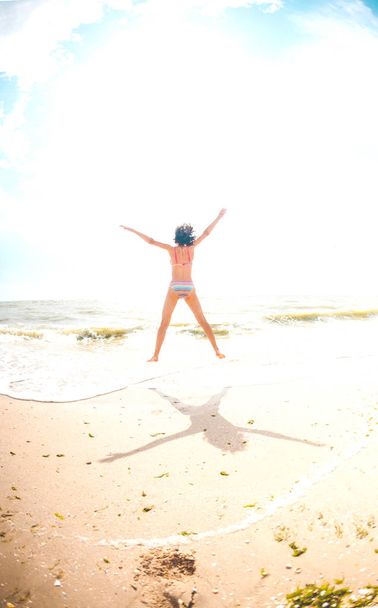 Una ragazza sta saltando sulla spiaggia
. - Foto, immagini