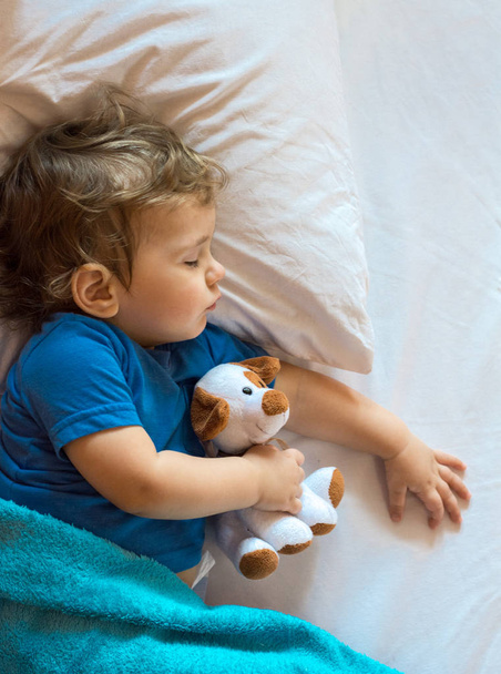 Schattig peuter slapen op het bed thuis met speelgoed. - Foto, afbeelding