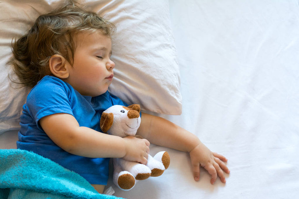 Schattige babyjongen slapen op het bed thuis met speelgoed. Vrije ruimte - Foto, afbeelding