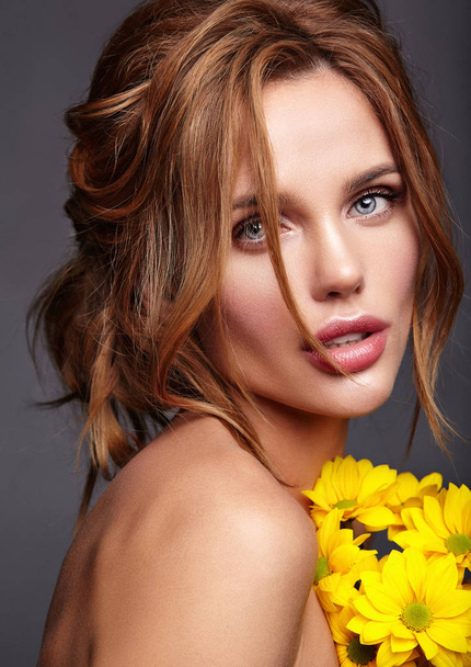 Beauty fashion portrait of young blond woman model with natural makeup and perfect skin with bright yellow chrysanthemum flower posing in studio - Foto, imagen