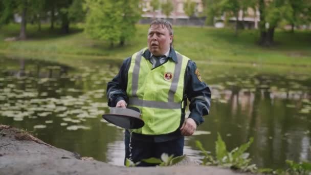 Dopravní důstojník pracovník vyšlapané a unavené leze z rybníka v městském parku - Záběry, video