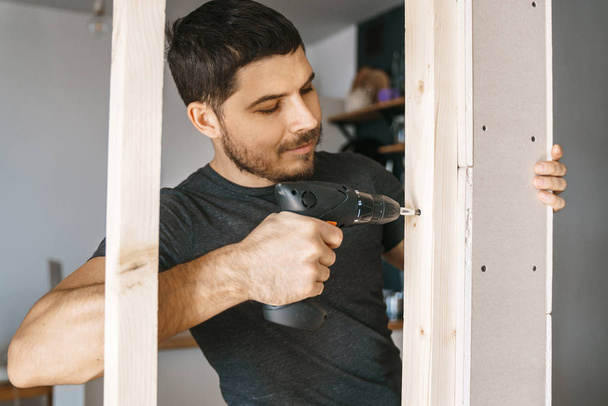 Otthoni ruhát a kezében csavarhúzóval férfi képmása javít egy fa építése, egy ablak az ő házában. Javítási magát. - Fotó, kép