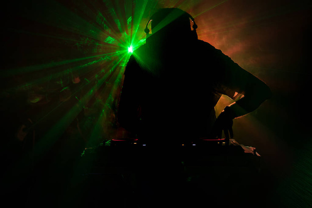Filature de DJ, mixage et gratter dans un Night-Club, mains de dj tweak diverses commandes de piste sur le pont du dj, lumières stroboscopiques et le brouillard, ou Dj mixes la piste dans la boîte de nuit à parti - Photo, image