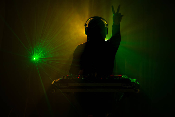 DJ iplik, karıştırma ve bir gece kulübünde tırmalamak, dj elinde çeşitli parça denetimlere dj's güverte, strobe ışıklar ve sis oynamak veya parti gece kulübünde parça Dj karışımları - Fotoğraf, Görsel