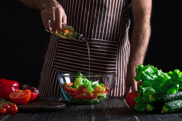 Cozinhar e conceito de casa - close-up de mãos masculinas aromatizando salada em uma tigela com azeite
 - Foto, Imagem