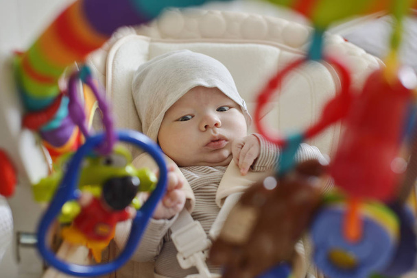 newborn  baby laying in bouncer chair and playing toy - Fotó, kép