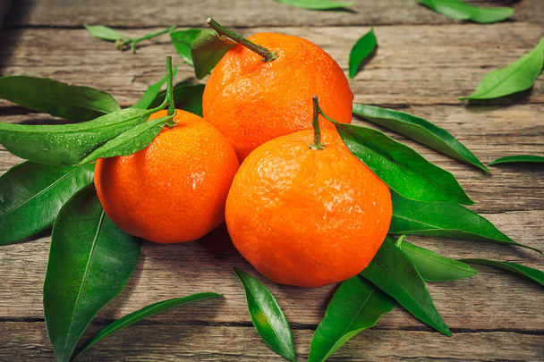 Fresh Clementine or Mandarin orange with leaves on wooden background. - Photo, Image
