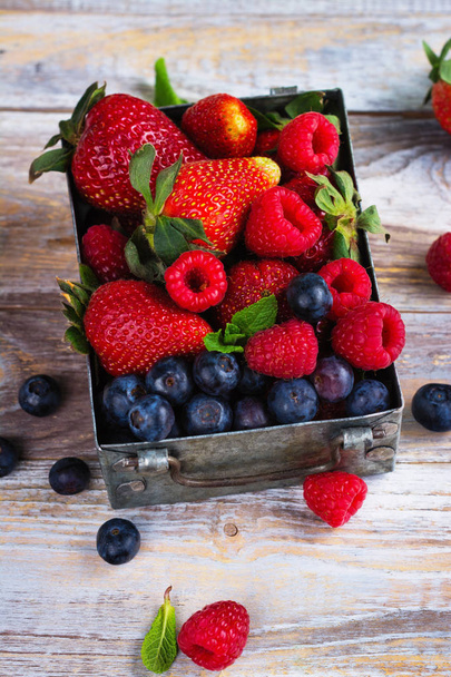 Fresh mix of berries in a metal box on white stone background - Photo, Image