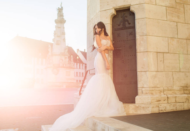 Woman at stone ancient tower in summer. Wedding fashion and beauty salon. Bride girl at wedding ceremony in castle. Fashion model or princess in dress. Sexy girl in white dress with stylish hair - Фото, изображение