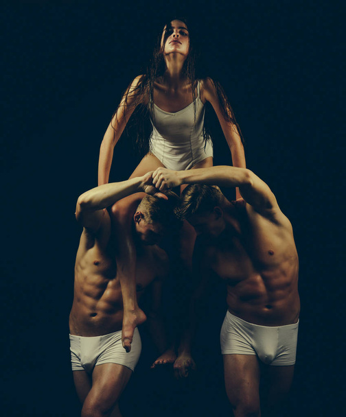 Twins men with muscular body and girl coach. twins with strong body hold gymnast girl isolated on black. - Foto, Bild