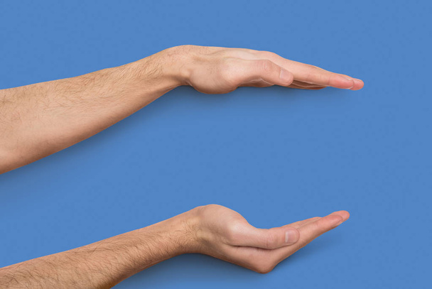 Чоловічі руки вимірюють невидимий предмет на бежевому фоні
 - Фото, зображення