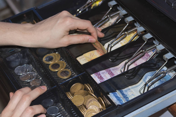 Verkoopster handen bij kassa met Braziliaanse geld notities en - Foto, afbeelding
