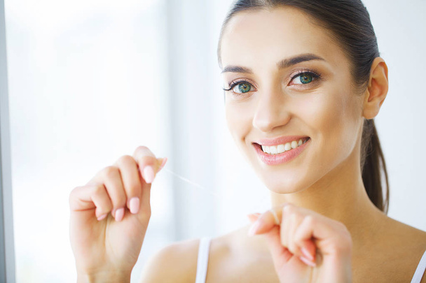 Soins des dents. Belle femme souriante soie dentaire saine dents blanches
 - Photo, image