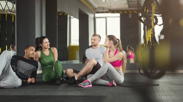 Group of sporty people sitting on floor at gym - Photo, Image