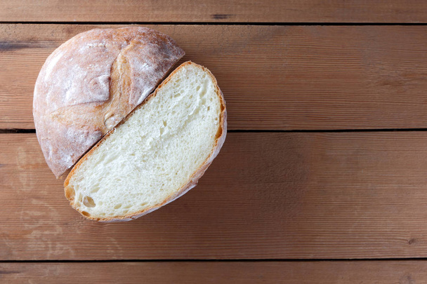 Pão meio cortado em um fundo de madeira, duas metades de pão de trigo de um fogão em placas de pinho, uma massa de farinha francesa para um designer, espaço de cópia, estilo rústico, fundo de madeira
 - Foto, Imagem