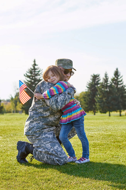 Μικρό παιδί με την σημαία των ΗΠΑ αγκαλιάζει τον πατέρα της. - Φωτογραφία, εικόνα