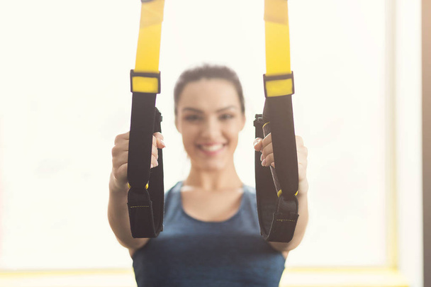 Woman performing TRX suspension training in gym - Foto, afbeelding