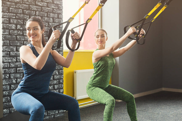 Женщины, проводящие тренировки по подвеске TRX в спортзале
 - Фото, изображение
