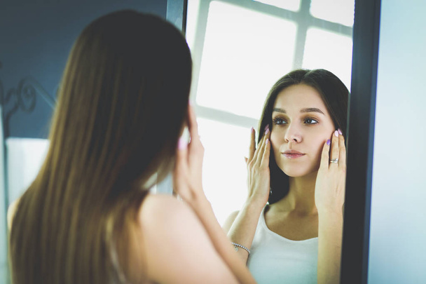 Young woman looking herself reflection in mirror at home - Photo, Image