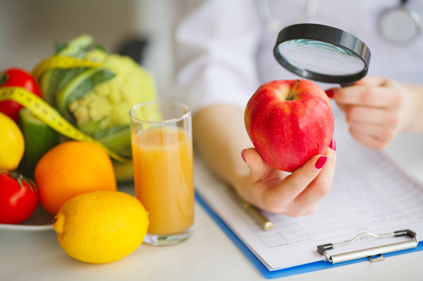 Algumas frutas como maçãs, kiwis, limões e bagas na mesa nutricionista
 - Foto, Imagem