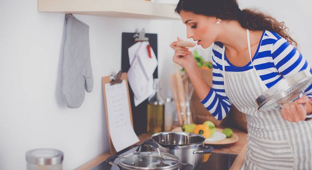 Nainen tekee terveellistä ruokaa seisoo hymyillen keittiössä
 - Valokuva, kuva