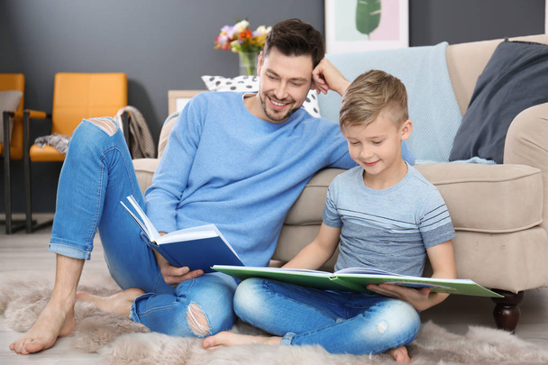 Little boy and his dad reading books at home - Foto, imagen