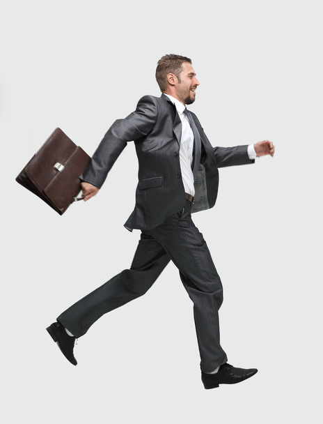 side view.cheerful businessman with briefcase stepping forward - 写真・画像