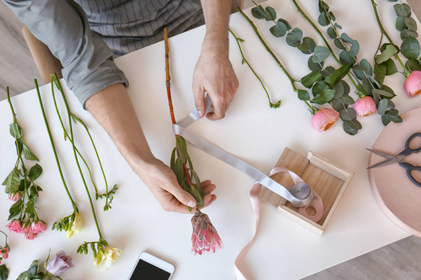 Male florist creating beautiful bouquet at table, top view - Photo, Image