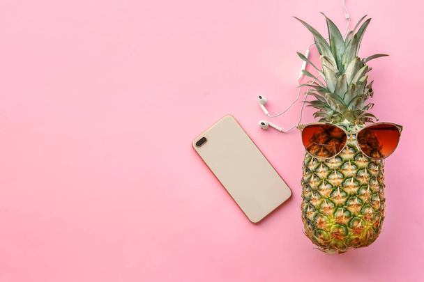 Fresh ripe pineapple with earphones and mobile phone on color background, top view - Photo, Image