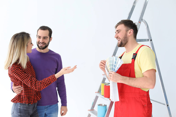 Male decorator and young couple with color palette on white background - Fotoğraf, Görsel
