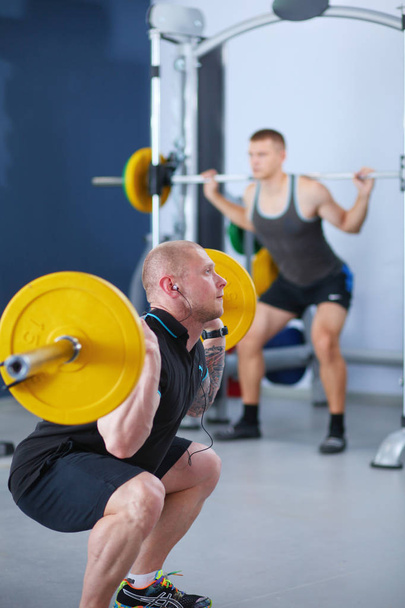 Bodybuilder with barbell in gym. Bodybuilder - Фото, изображение