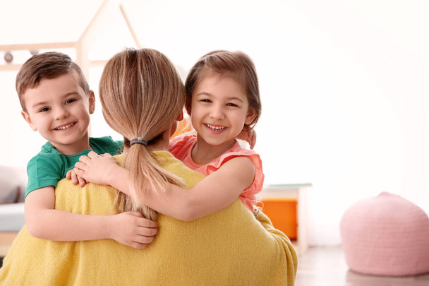 Cute little children hugging their nanny at home - Valokuva, kuva
