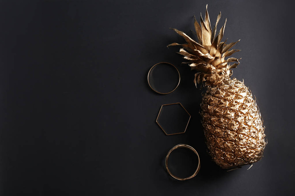 Golden pineapple and bracelets on dark grey background, flat lay - Fotoğraf, Görsel