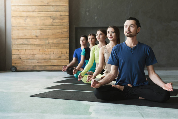 Giovani donne e uomini in classe di yoga, rilassarsi posa meditazione
 - Foto, immagini