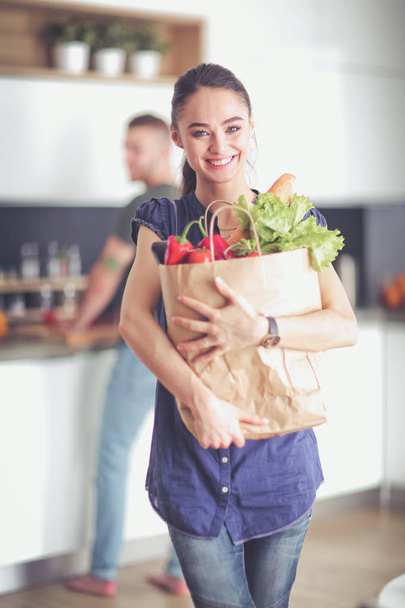 Young couple in the kitchen , woman with a bag of groceries shopping - Photo, image