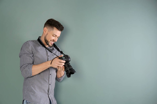 Male photographer with camera on grey background - Foto, afbeelding