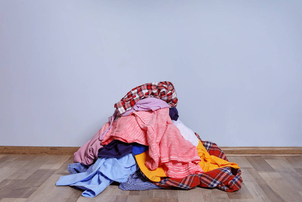 Pile of dirty clothes on floor near color wall - Фото, зображення