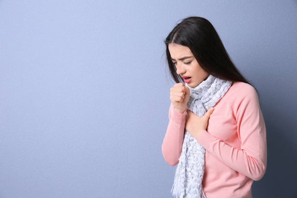 Young woman coughing on color background - 写真・画像