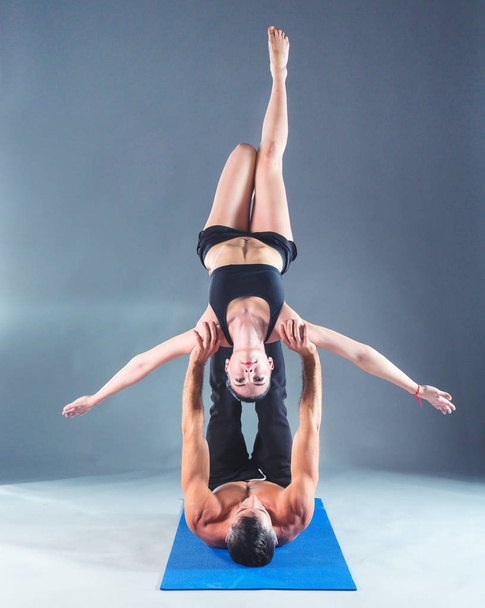 Young couple practicing acro yoga on mat in studio together. Acroyoga. Couple yoga. Partner yoga. - Photo, Image
