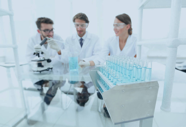 background image of scientists studying blue liquid in a flask - Fotó, kép