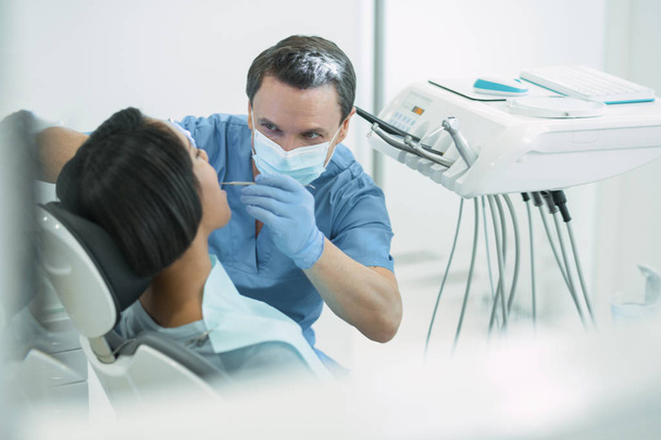 Experienced male dentist examining his patients teeth - Foto, Imagem