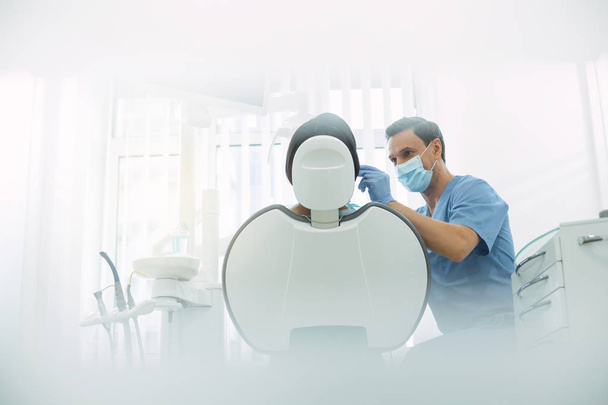 Delighted male dentist examining his patients teeth - Фото, изображение