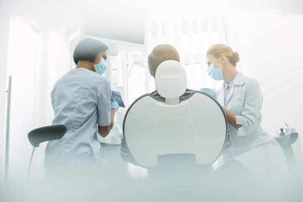 Experienced dentists sitting near the patient - Photo, image