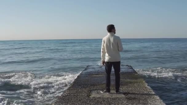 Человек смотрит вокруг, стоя на пирсе в море в солнечную погоду, ясный горизонт
 - Кадры, видео
