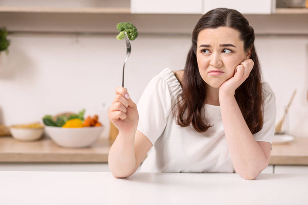Displeased beautiful woman eating vegetables - Foto, afbeelding
