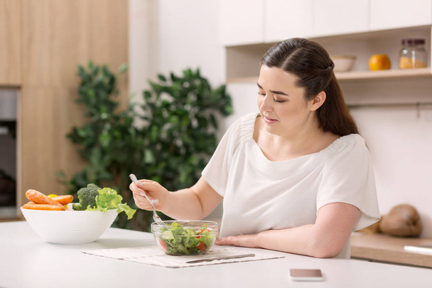 Focused attentive woman mixing salad - Foto, afbeelding