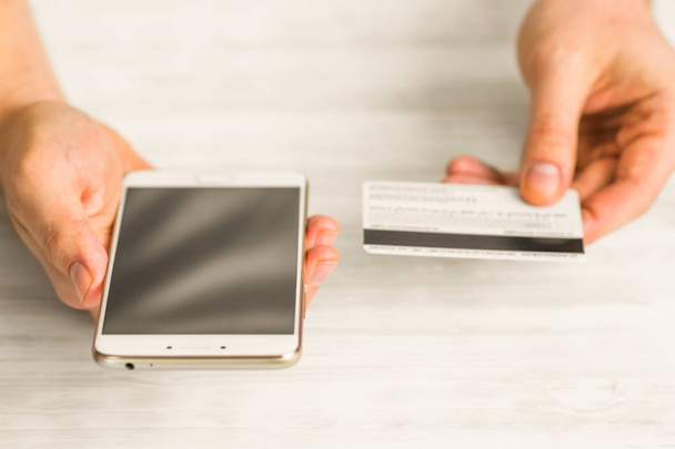 el kredi kartı tutan ve smartphone kullanarak. Online ödeme plastik kart. Beyaz bir adam elinde smartphone ve kredi kartı - Fotoğraf, Görsel