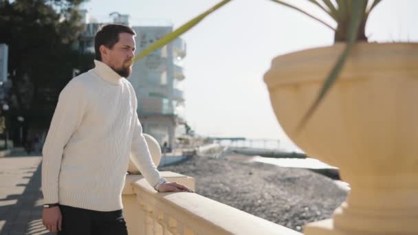 Gondolkodó ember nézi, a tenger, kő kerítés város partra hajló - Felvétel, videó