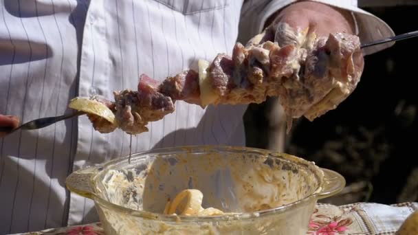 Fat Man Puts the Marinated Raw Meat on a Skewer for a Shish Kebab on Nature. Slow Motion - Felvétel, videó